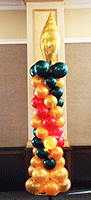 This six foot tall column of gold, red and green balloons is topped by a gold mylar'flame' balloon