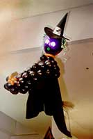 Balloon sculpture of a witch flying high on her broom as a ceiling decoration for a Halloween party