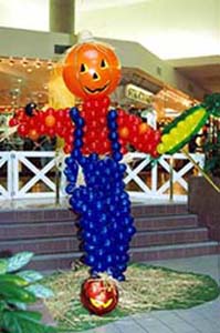 A six foot tall balloon sculptire of a scarecrow complete with coveralls and an ear of corn.