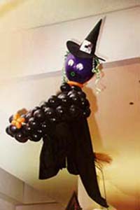 A balloon witch sculpture flying on her broomstick as a ceiling decoration for a halloween event