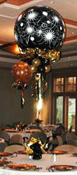 This centerpiece consists of a black 30 inch bubble balloon adorned with white starburst designs and gold and black collar balloons floats five feet above each table from a decorative base 