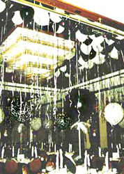 The ceiling above this dance floor is filled with floating black and white balloons each suspending a mylar streamer.