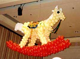 Balloon sculpture of a giant rocking horse suspended from this event ceiling to create the impression that guests are surrounded by toys bigger than they are
