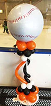 This Balloonatics baseball-themed centrpiece has a giant baseball balloon on top of a stqnd decorated in twisting balloons in team colors.