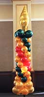 Column of gold, red and black balloons shaped like a candle complete with a gold colored mylar balloon flame